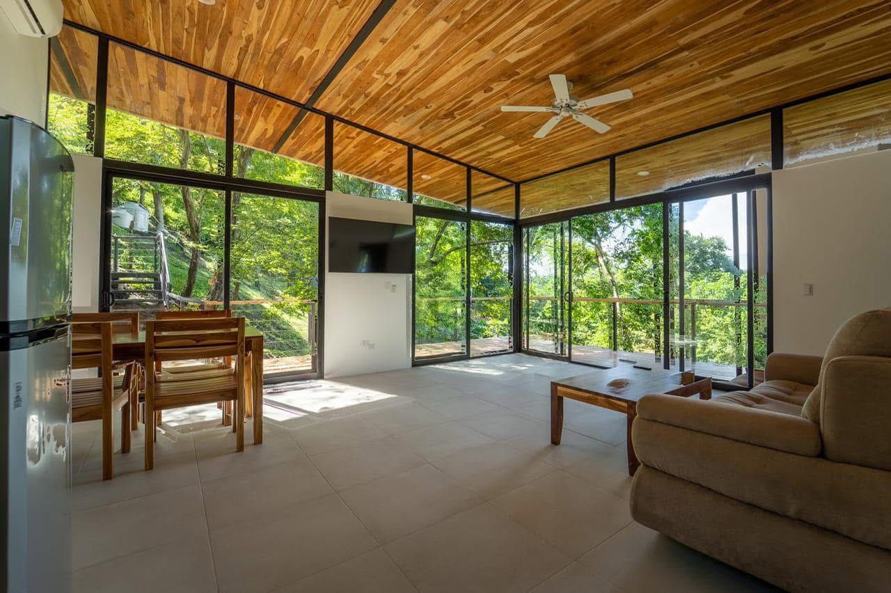 Casa Buenos Aires — Matta Ruiz living room with wood-slat ceiling and floor-to-ceiling glass opening to the tropical garden.