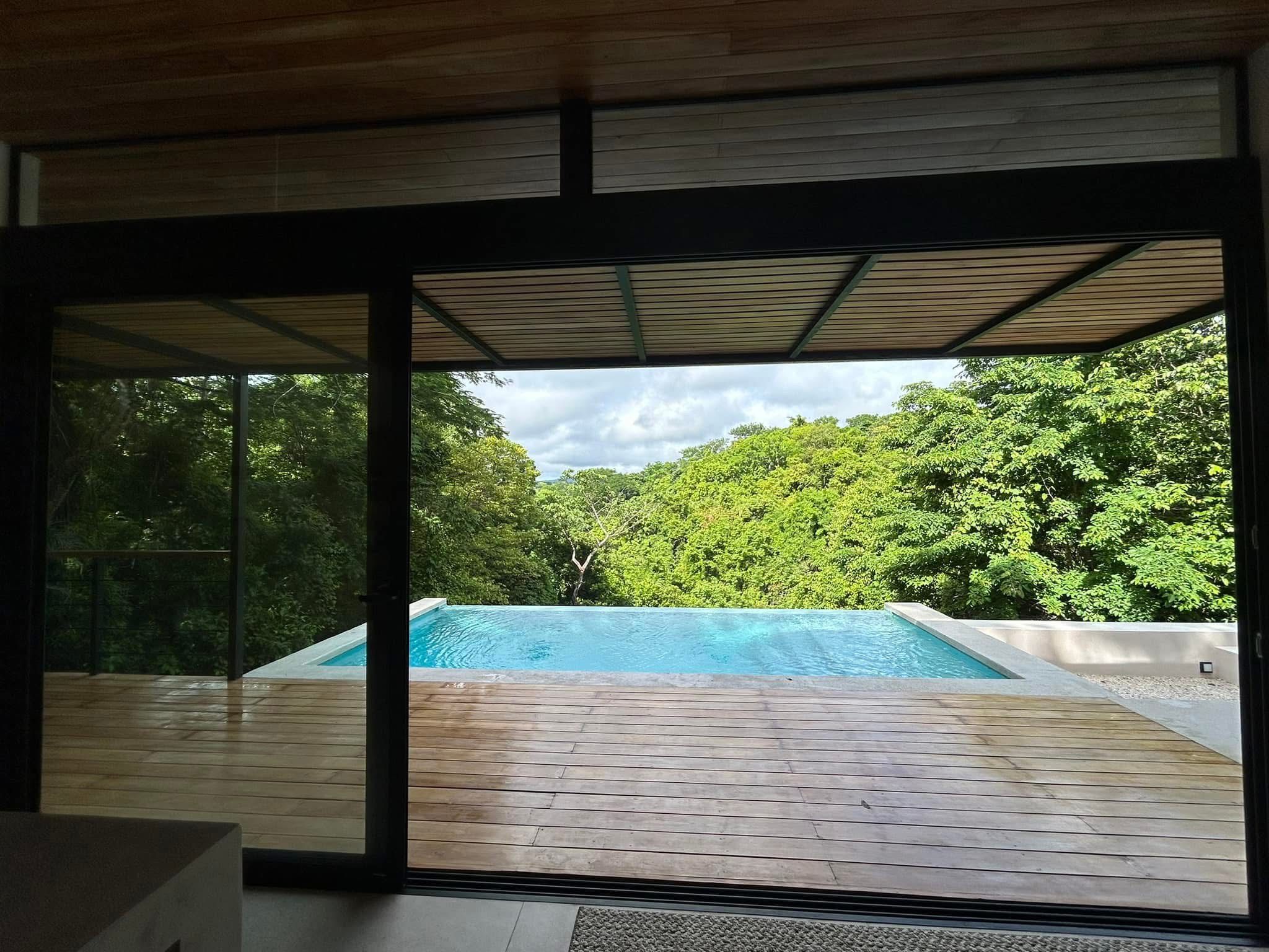 View from inside Casa Delicias through the sliding doors onto the private pool with the jungle canopy beyond.