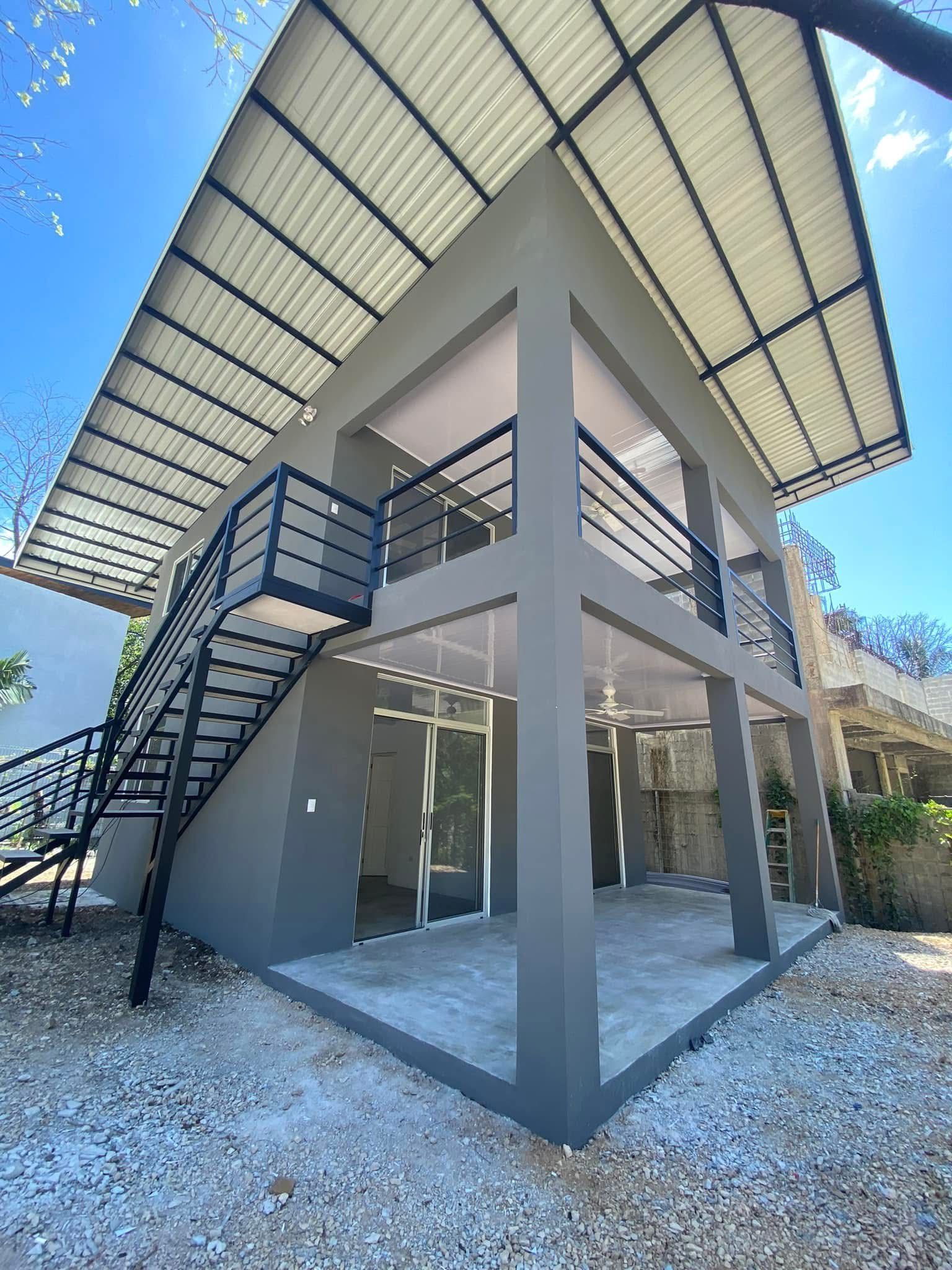 Gray concrete two-story Matta Ruiz construction with exposed steel stairs and standing-seam metal roof in Santa Teresa.